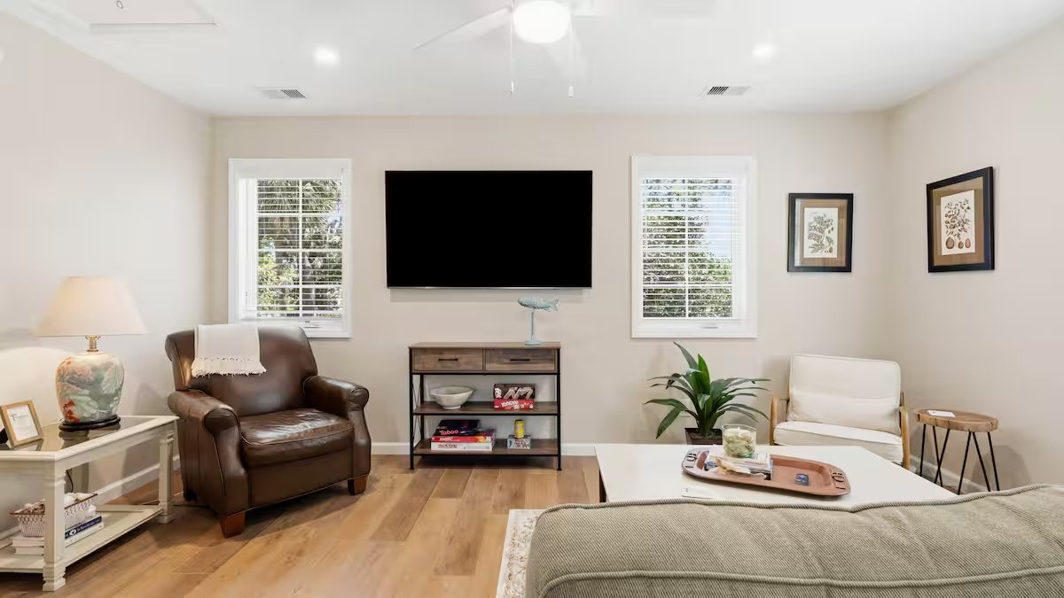 Light-filled living room with leather reading chair, plush sofa, and a 65-inch TV